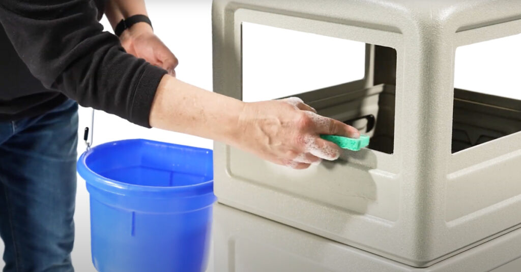 trash receptacle being cleaned with a cloth